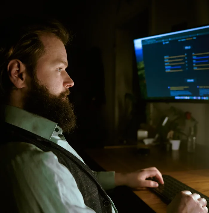 Sven Buss am Schreibtisch vor einem Monitor mit Code